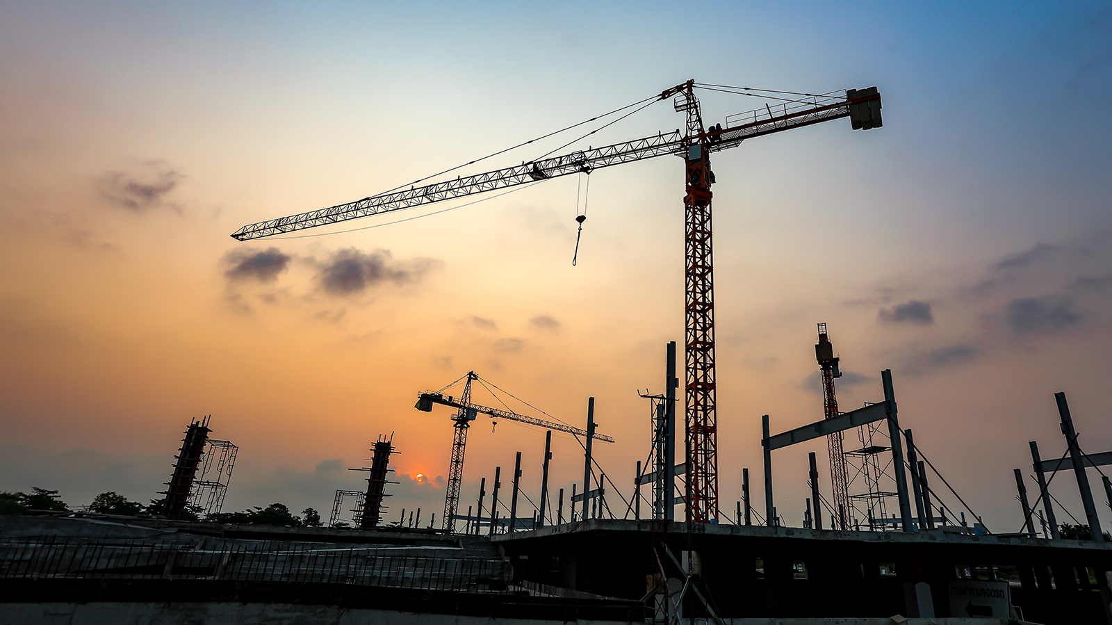 New construction site with crane and mechanical equipments on sunset background.