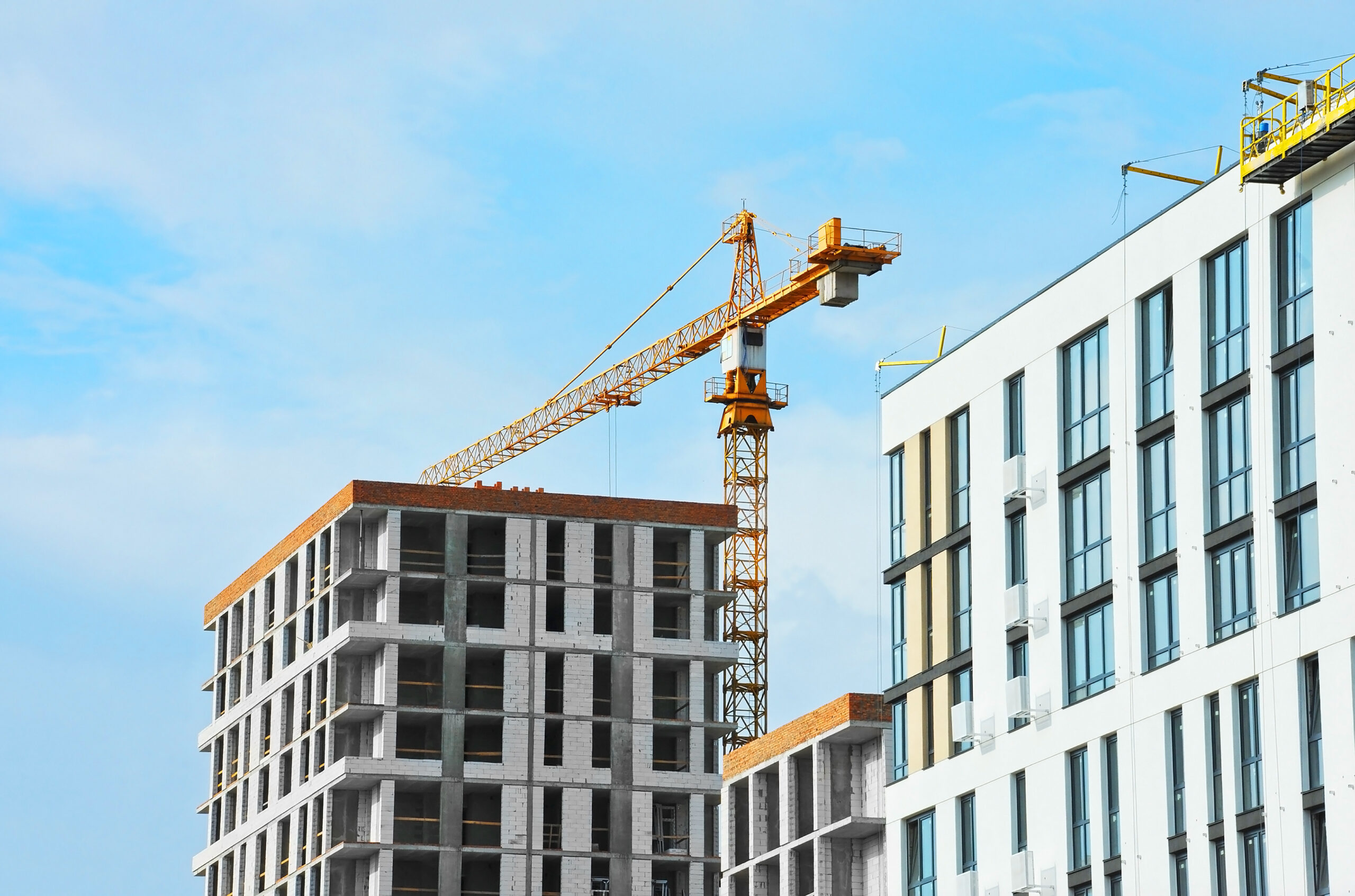 Crane and building under construction against blue sky